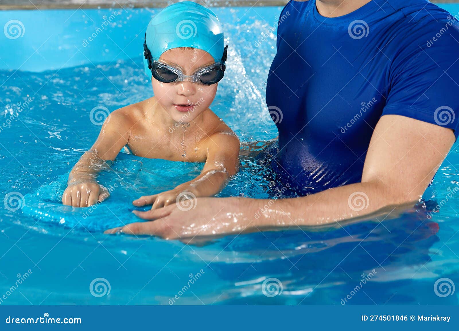 Little Boy Learning To Swim in Indoor Pool with Pool Board and Trainer