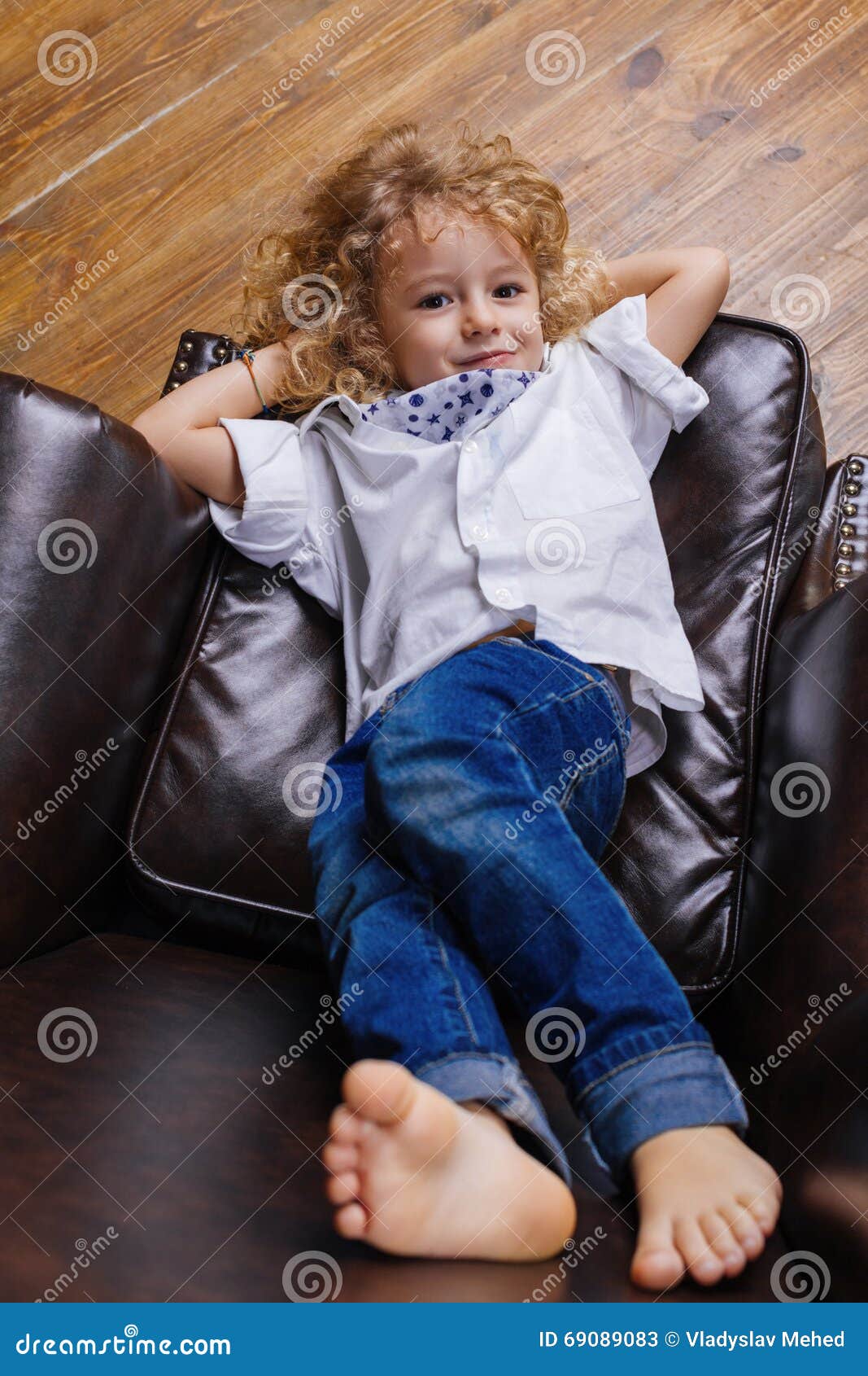Little Boy Lying On Chair. Little Boy Lying On Brown Leather Chair
