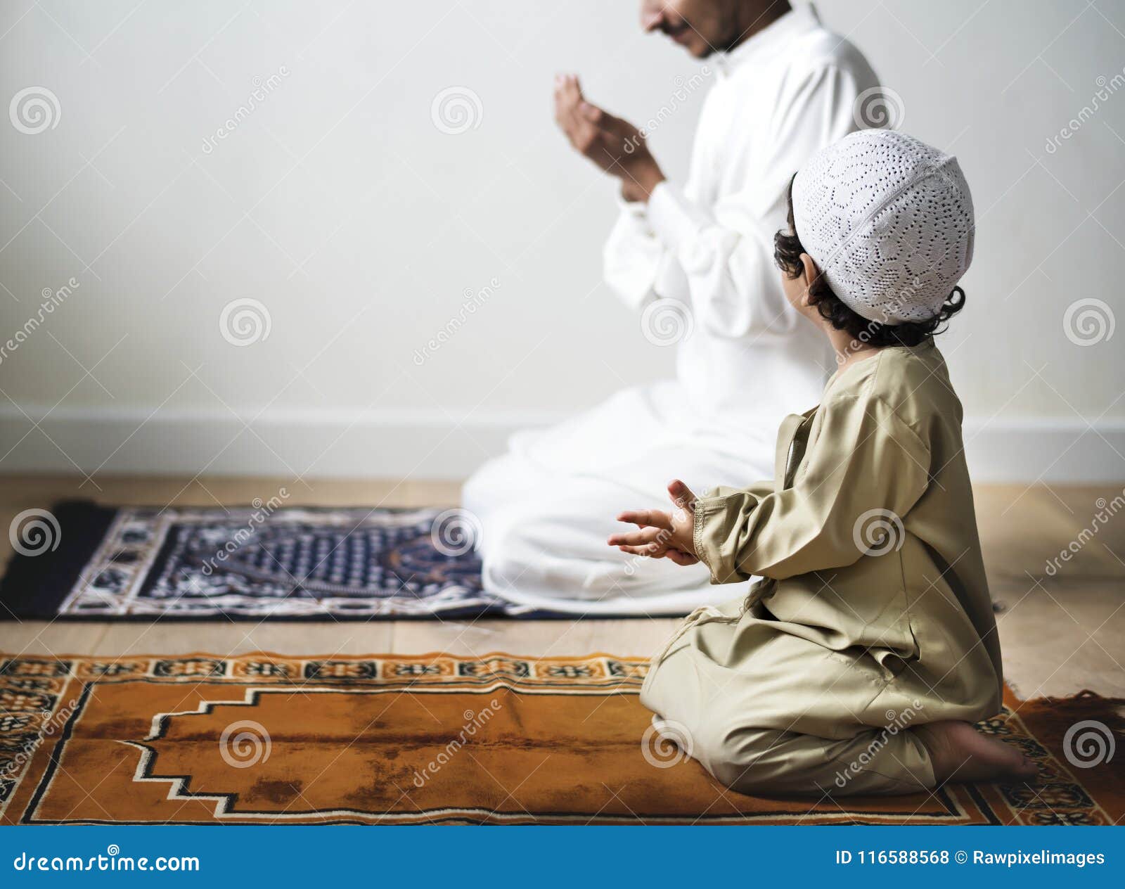 little boy praying alongside his father during ramadan