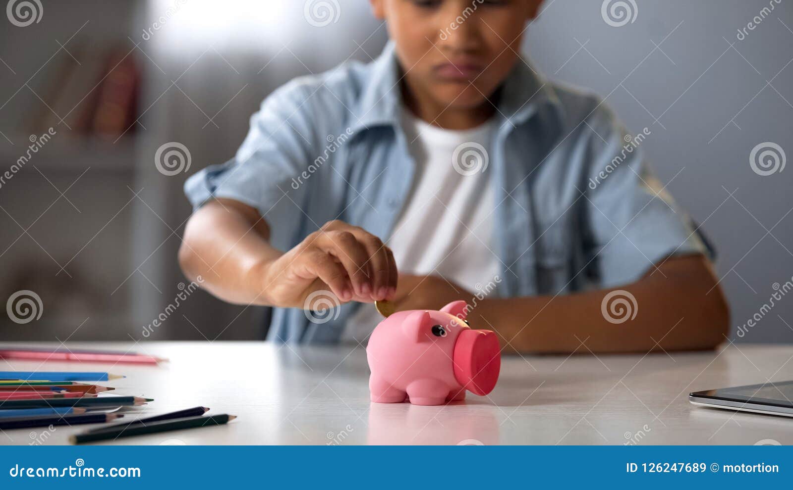 little boy putting pocket money in piggy bank, raising funds for desired toy