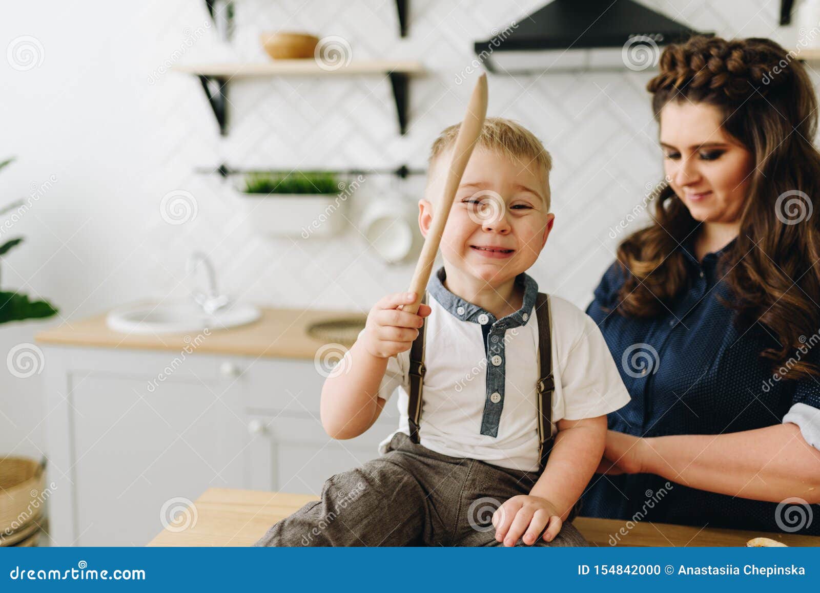 https://thumbs.dreamstime.com/z/little-boy-sitting-kitchen-table-playing-kitchen-tool-smiling-happily-his-mother-behind-him-little-154842000.jpg