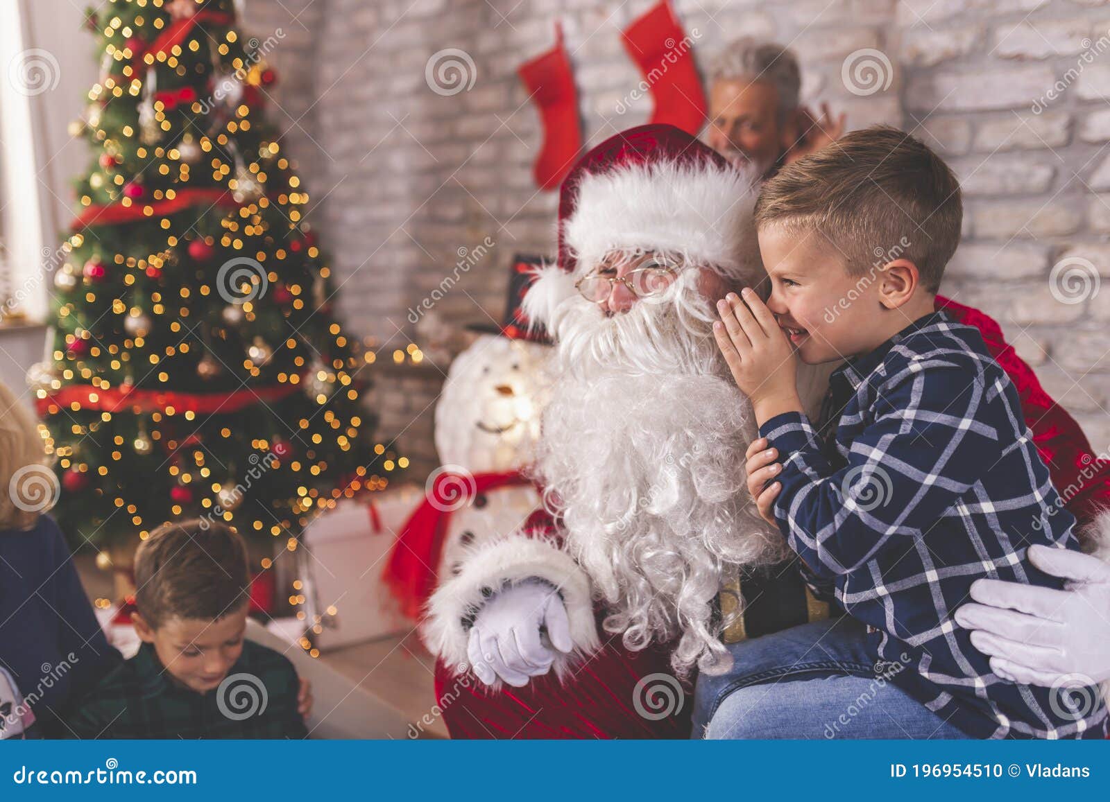 little boy sitting in santas lap whispering wishes for christmas presents