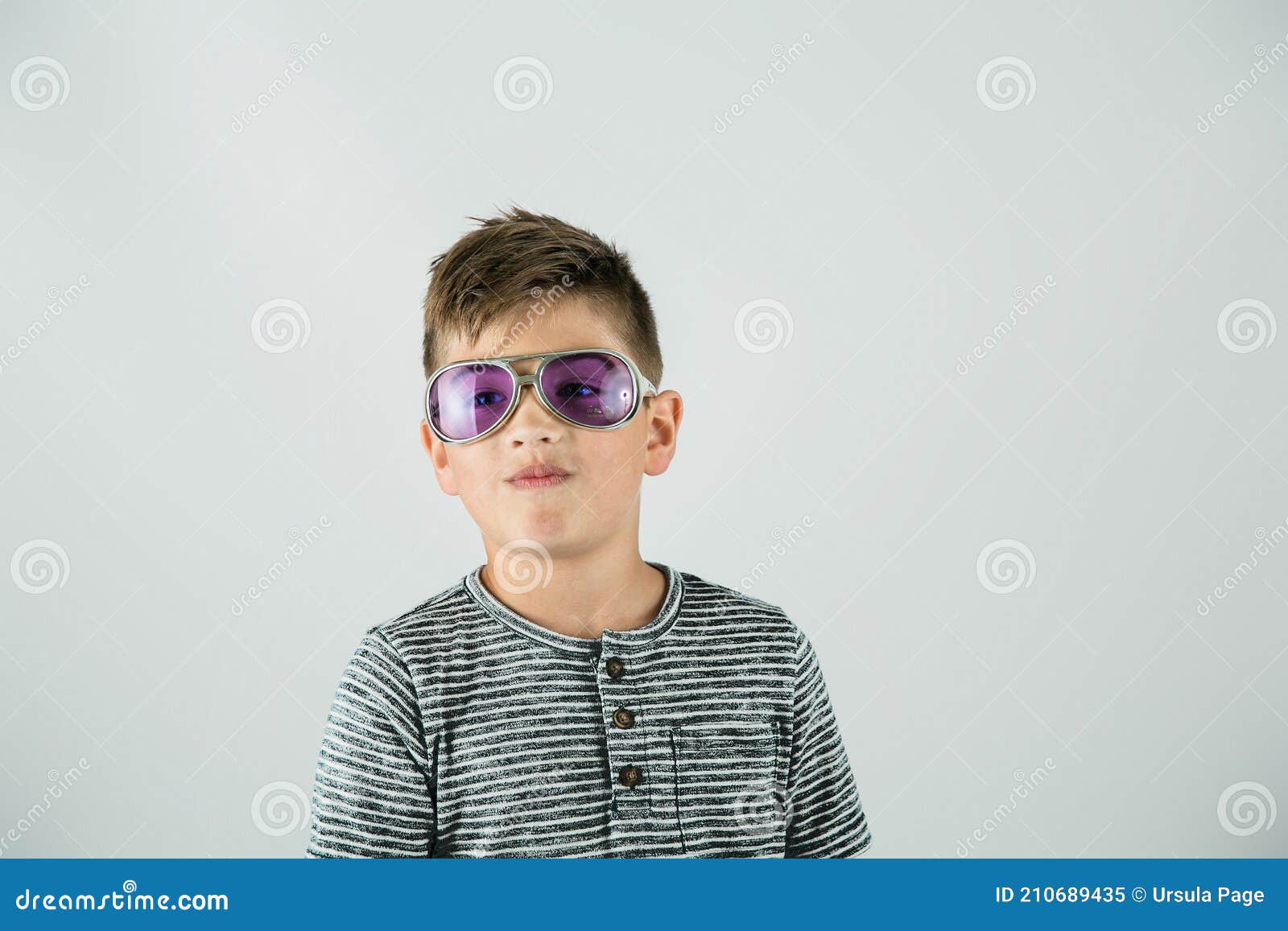 little caucasian boy standing in a studio setting on a white backdrop with rock star purple sunglasses and attitude.