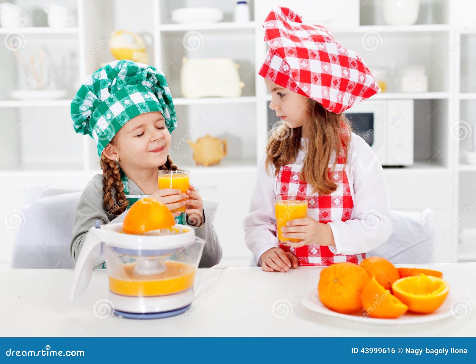 Little chef girls tasting the orange juice they made. Little chef girls tasting the fresh orange juice they made - healthy nutrition concept