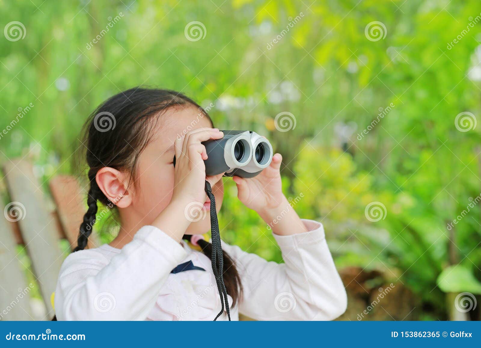 little child girl in a field looking through binoculars in nature outdoor. explore and adventure concept