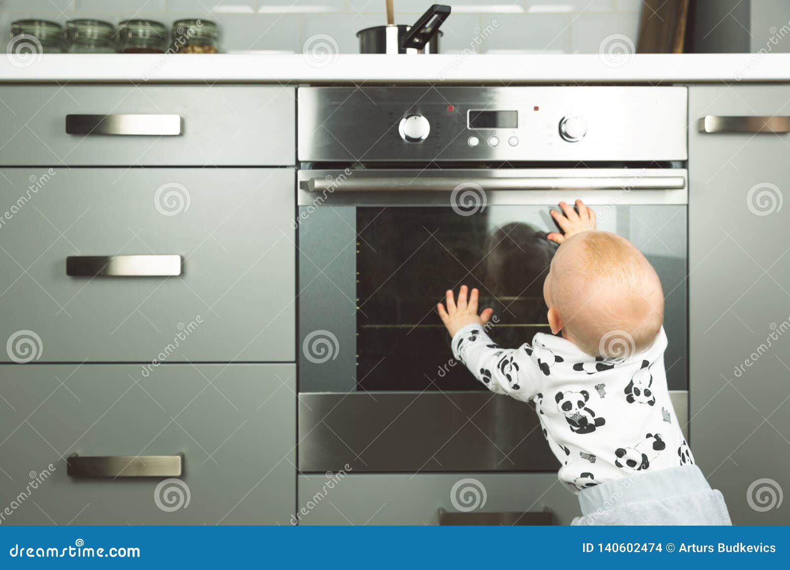 Little Child Playing with Electric Stove in the Kitchen. Baby Safety in