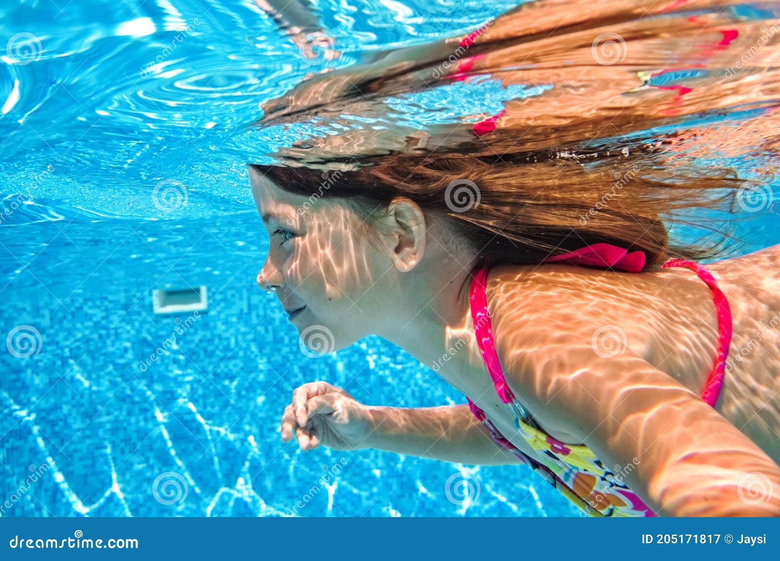 Child swims in pool underwater, happy active girl in 