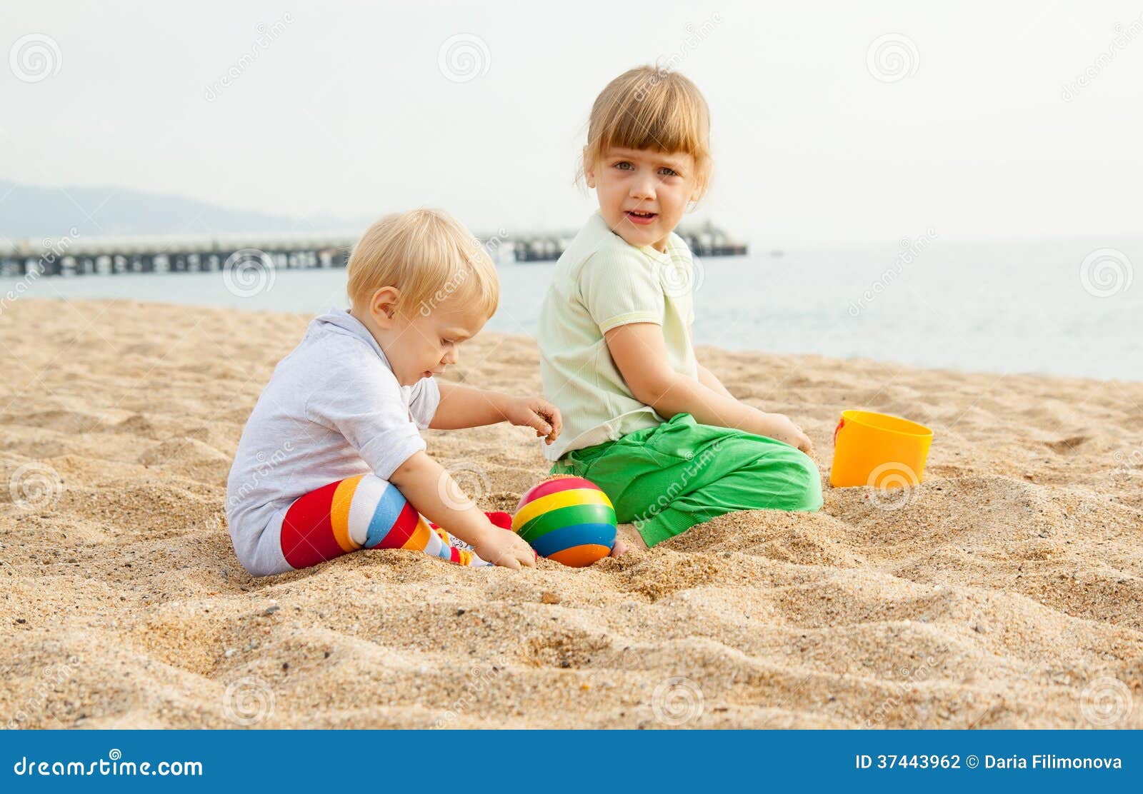 Child Playing In The Water In The Sand Wearing Blue Hi Res Stock