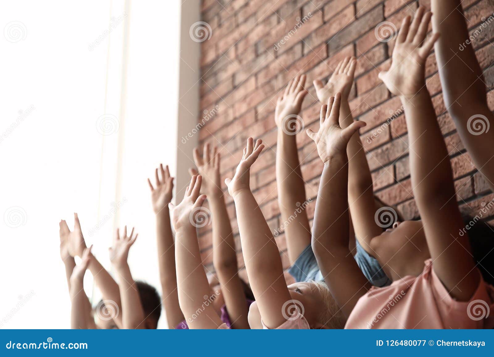 little children raising hands together indoors