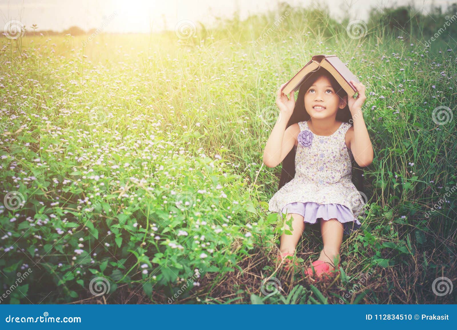 Little Cute Asian Girl Cover Book on Her Head at Nature. Stock ...