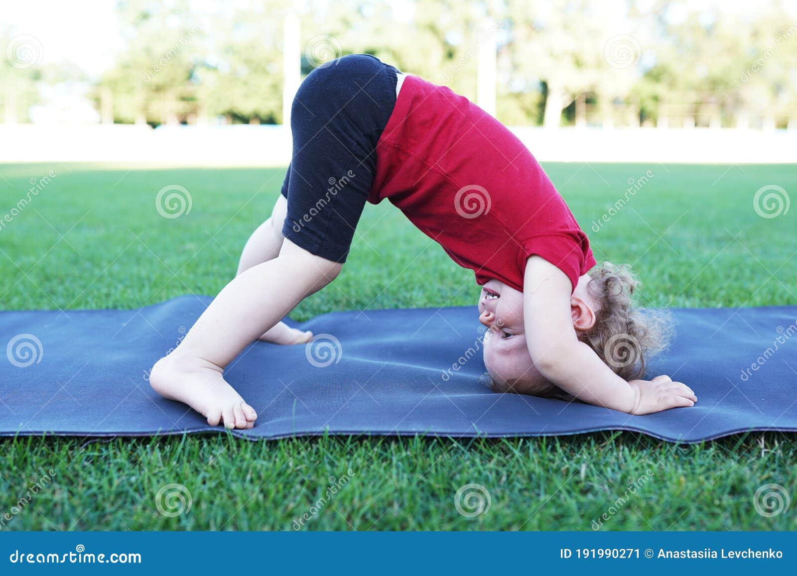 Little Cute Baby Girl Doing Yoga Exercise on the Grass at