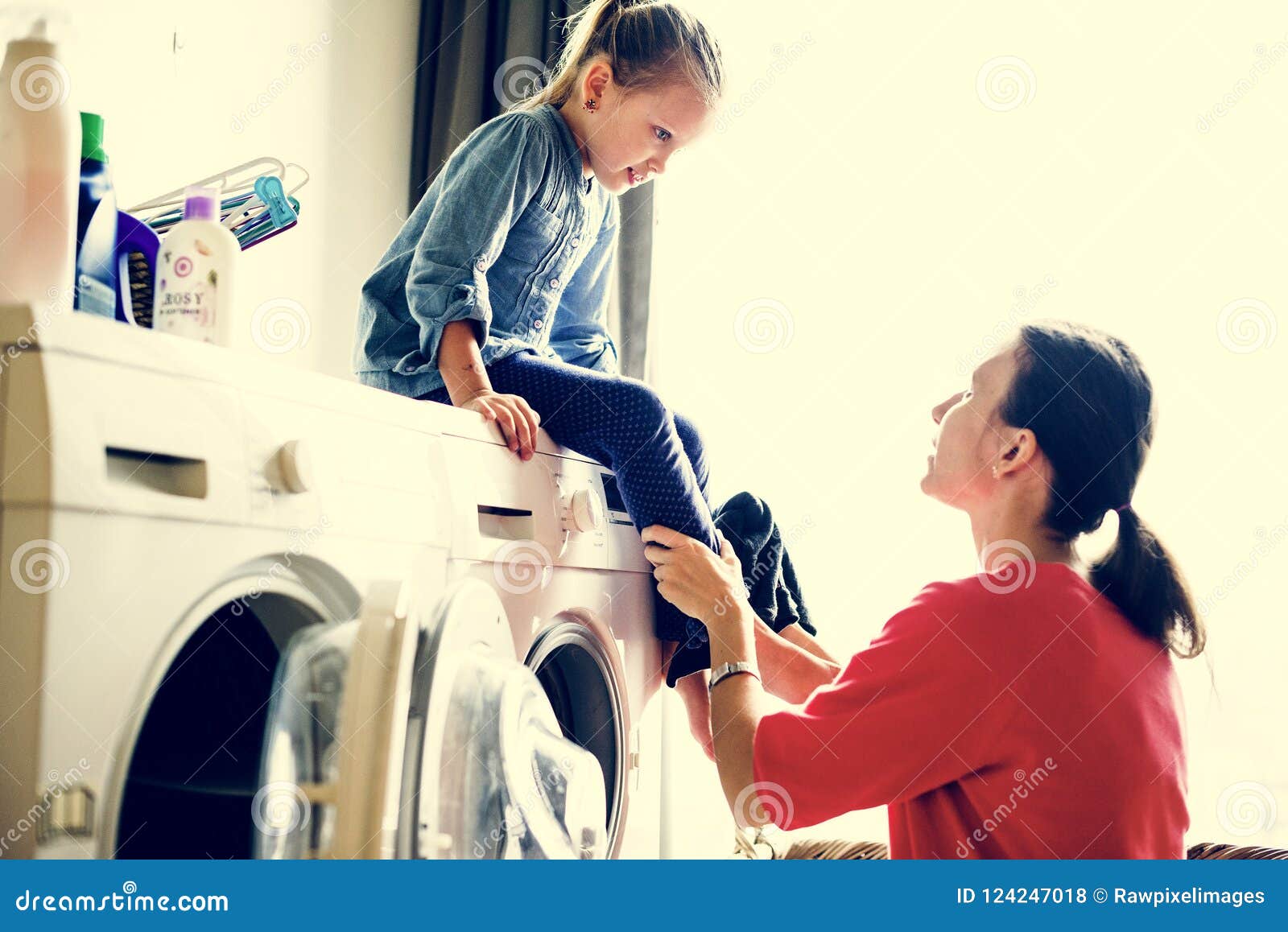 little daughter sitting on laundry machine