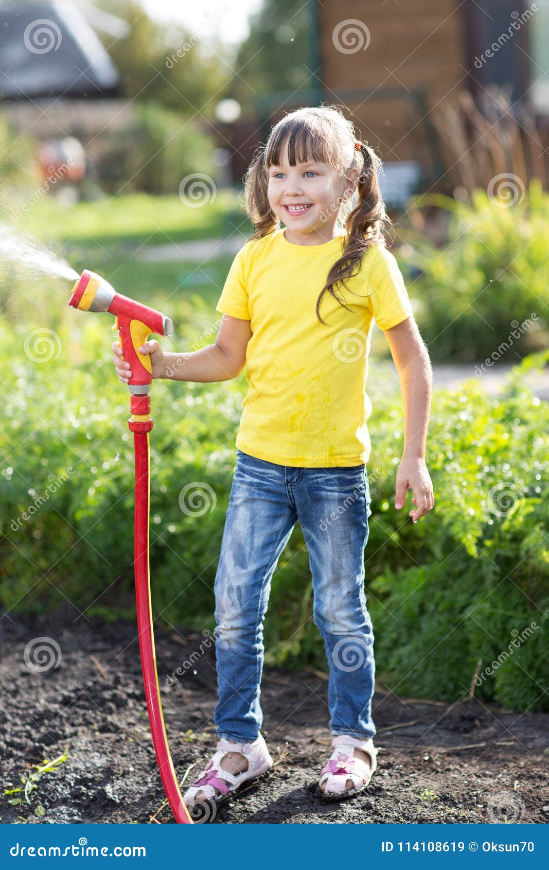 little gardener girl watering with hosepipe