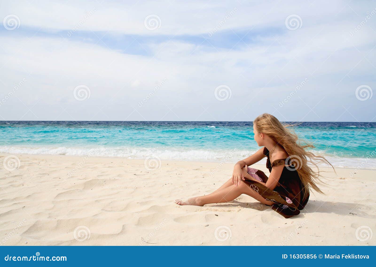 Little girl on a beach. Thoughtful little girl sitting near ocean in a dream