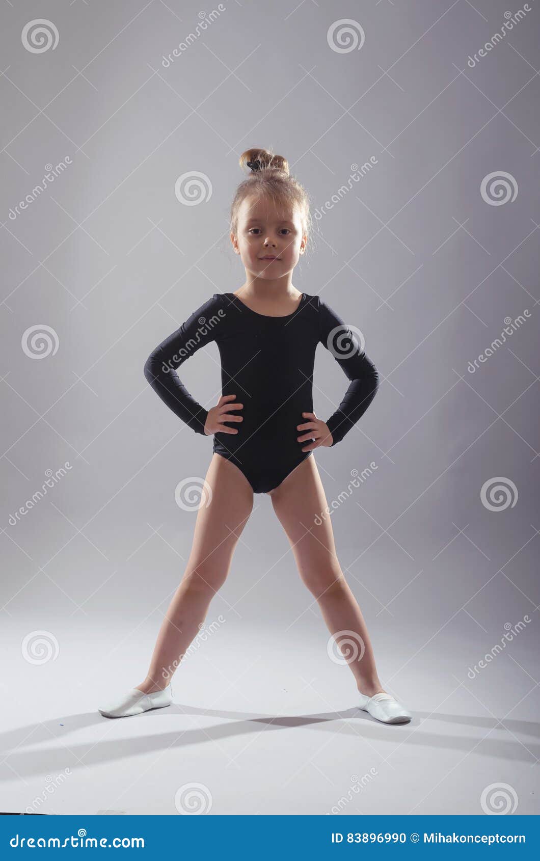 Little Girl in Black Tights Dancing on a Gray Background. Stock