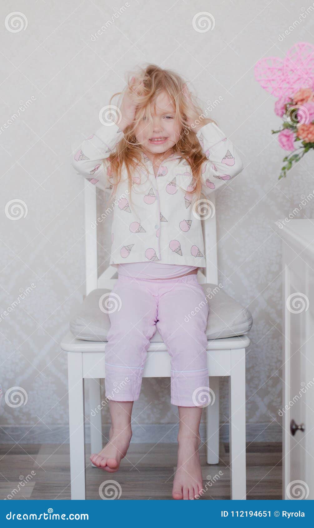 Little Girl Blonde Sitting On A Chair In Her Pink Pajama Top