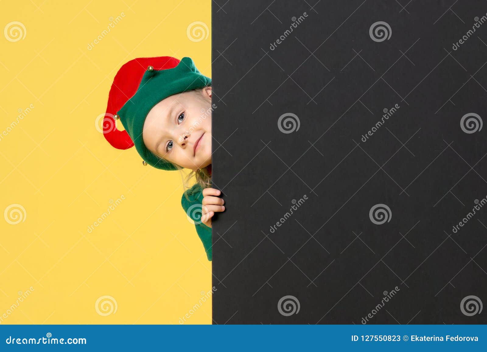 Little Girl In A Christmas Elf Costume On A Yellow