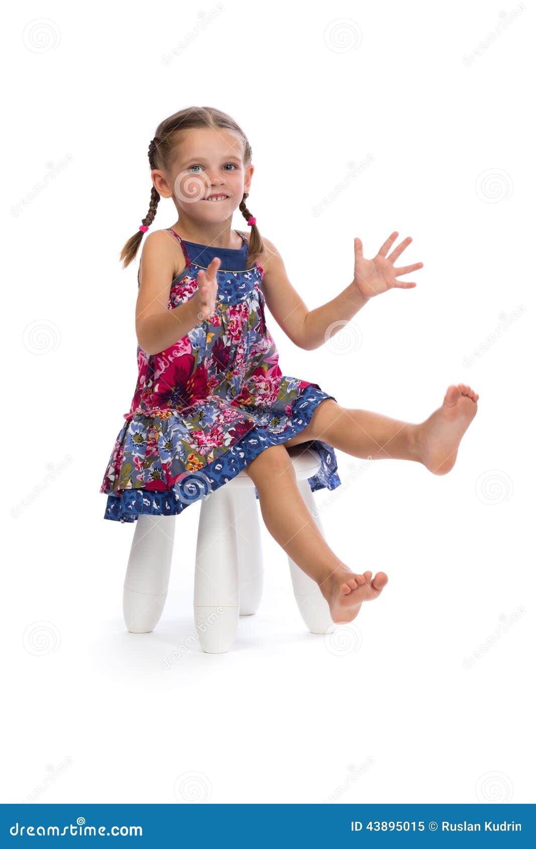 Little girl in a colored dress on a chair in the studio, isolate on white.