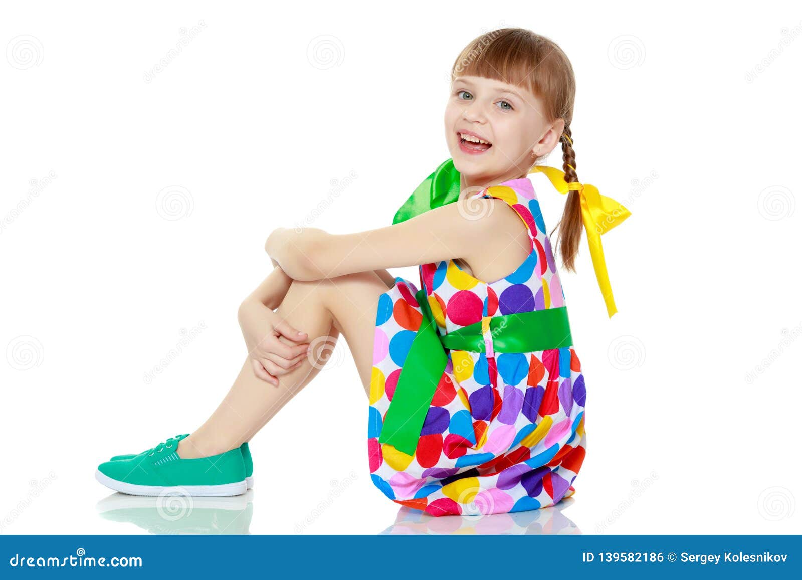 A Little Girl in a Dress with a Pattern from Multi-colored Circl Stock ...