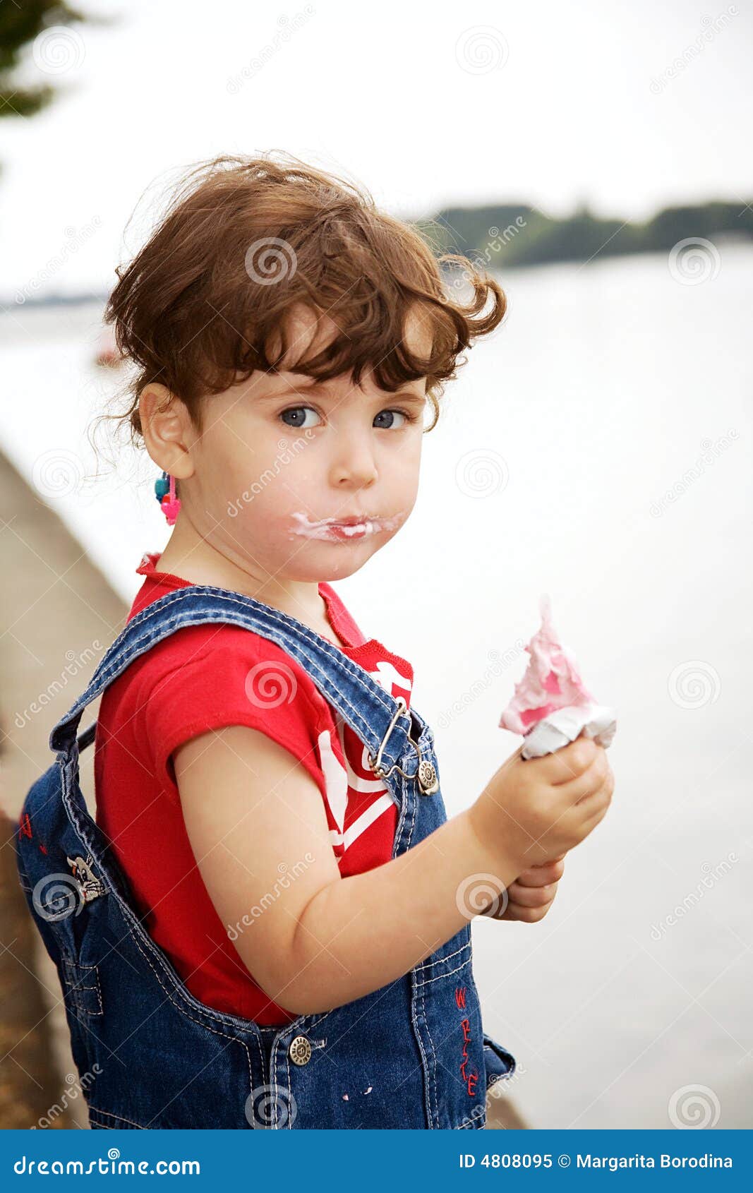 A little girl is eating strawberry ice-cream