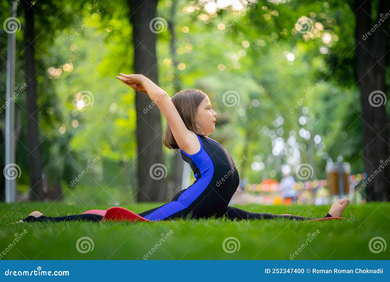 A Little Girl is Engaged in Meditation and Stretching in the Park. she ...