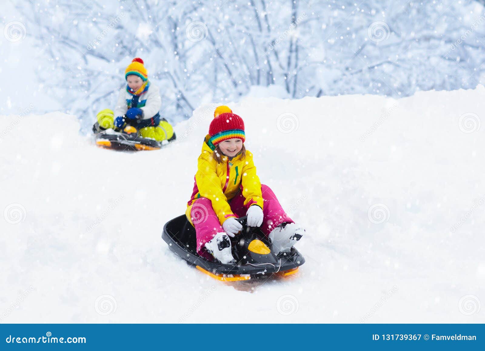 little girl enjoying a sleigh ride. child sledding. toddler kid riding a sledge. children play outdoors in snow. kids sled in the