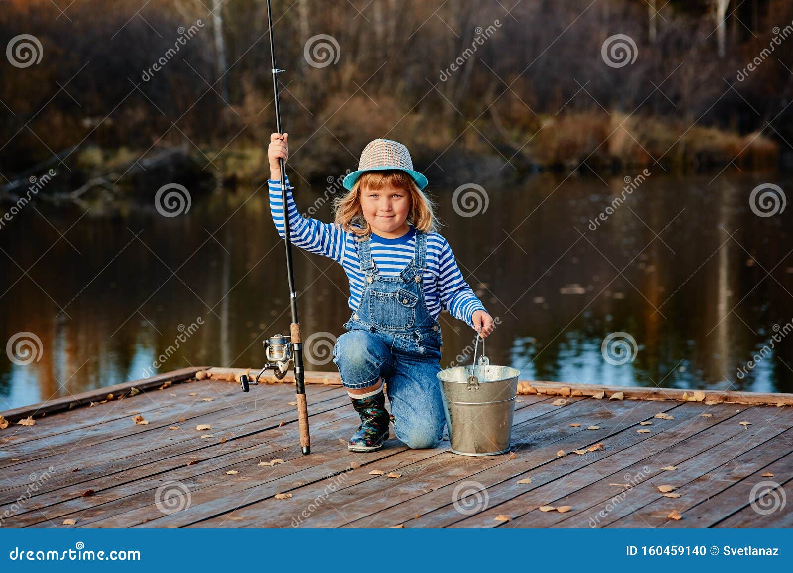 Little Girl Fisherman with a Fishing Rod and a Bucket of Fish on a