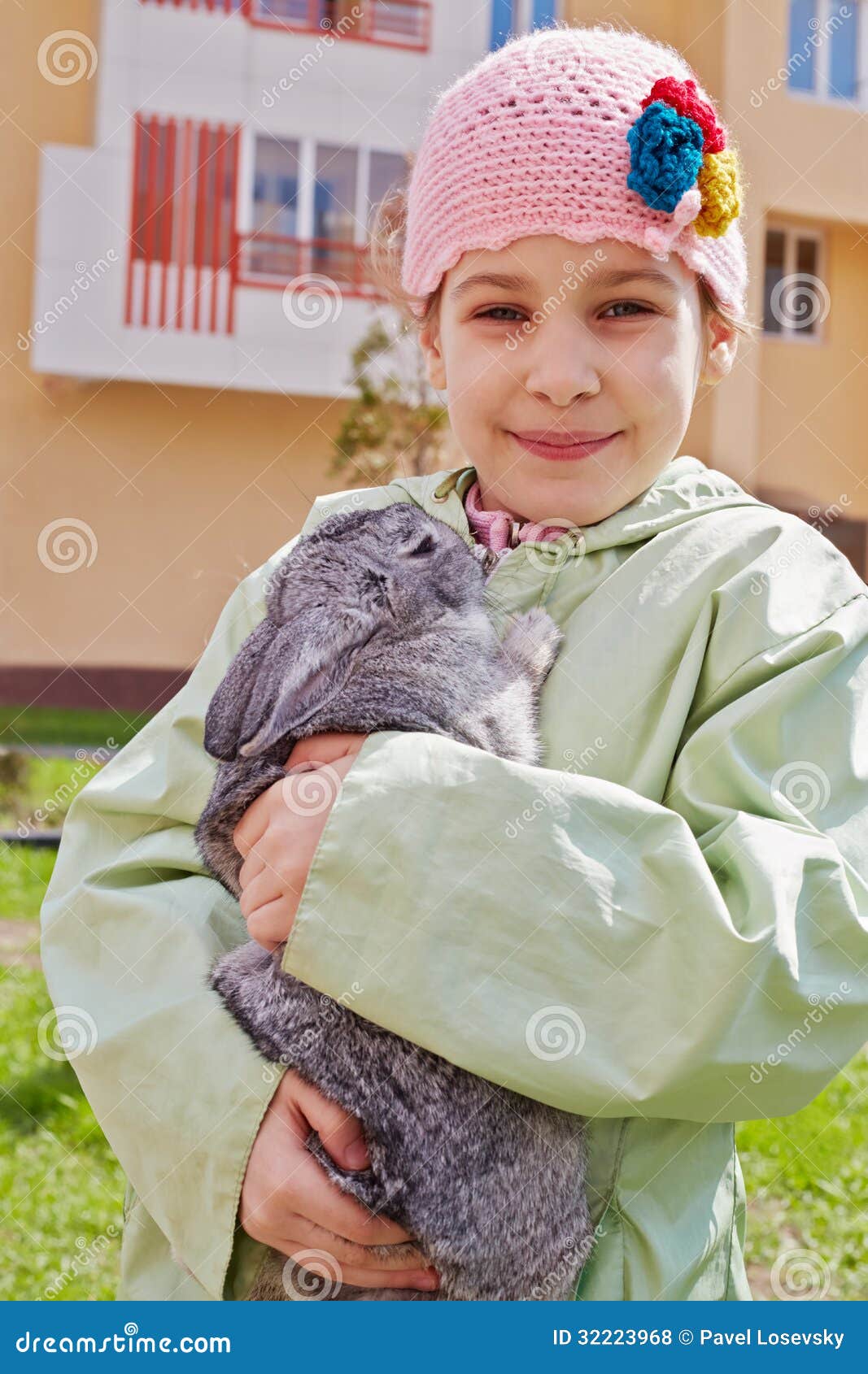 little girl in greenish jacket holds rabbit