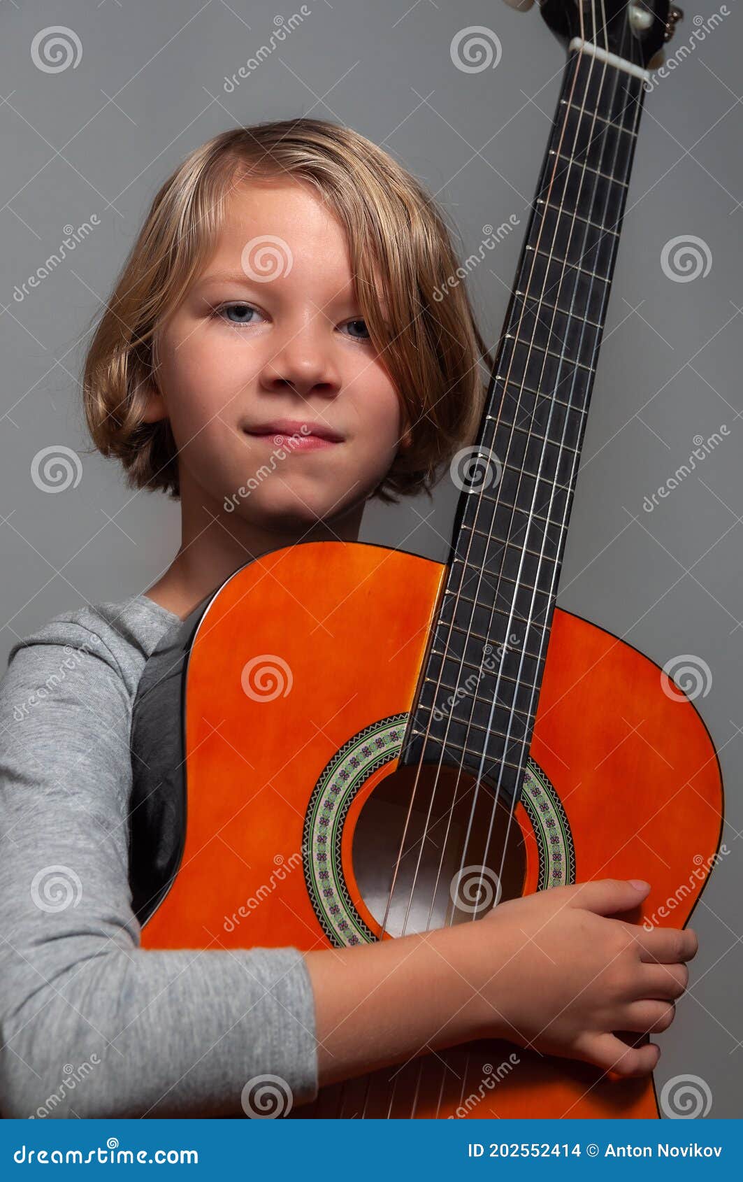Little girl with guitar on grey background. High quality photo