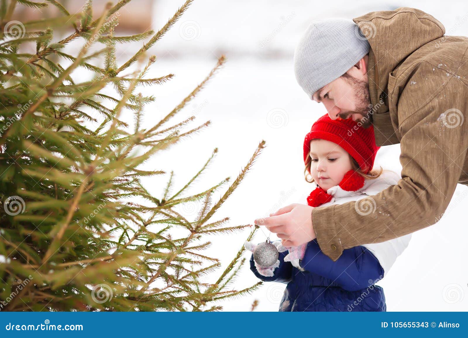 A Little Girl Helps Her Father Decorate a Christmas Tree Outdoors ...