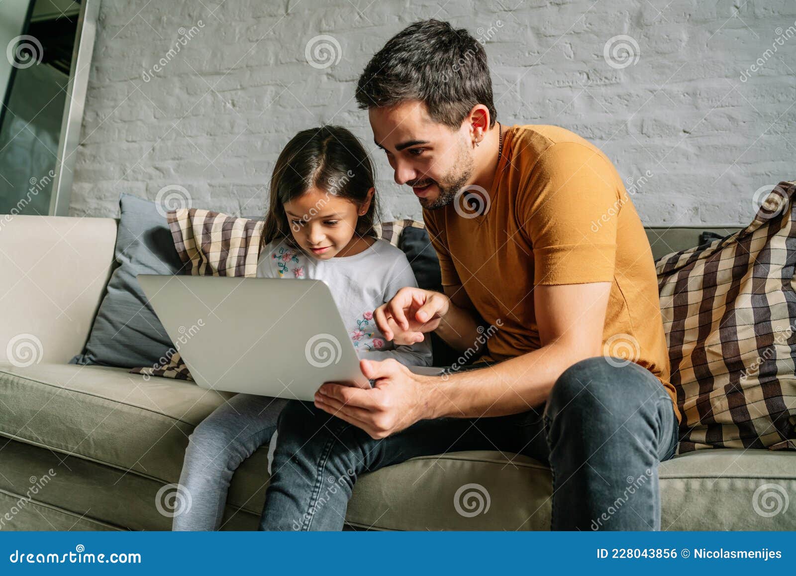 little girl and her father using a laptop together at home.