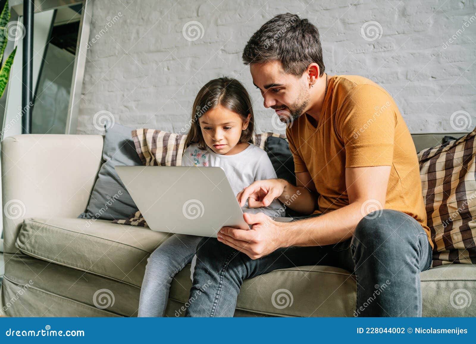 little girl and her father using a laptop together at home.