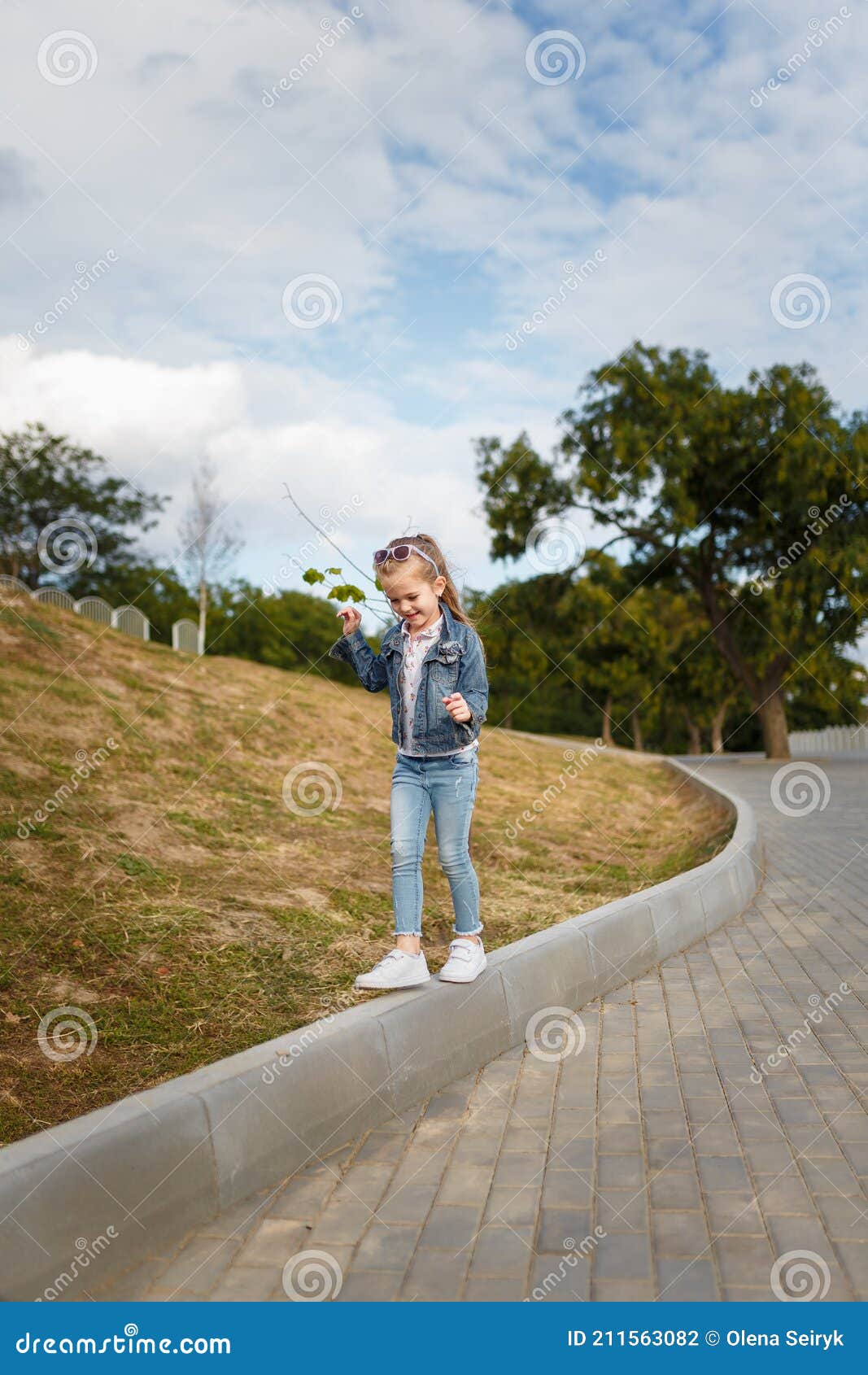 Little Girl in Jeans Jacket Playing and Walking Outdoors in Spring Park