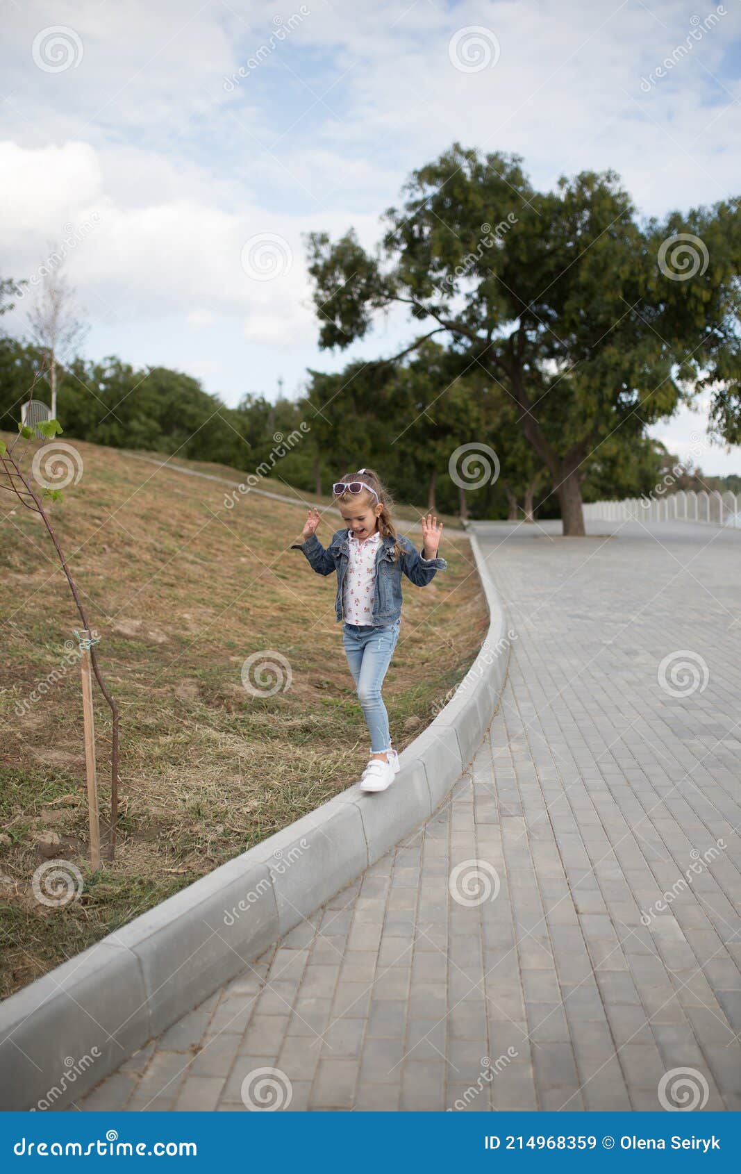 Little Girl in Jeans Jacket Playing and Walking Outdoors in Spring Park