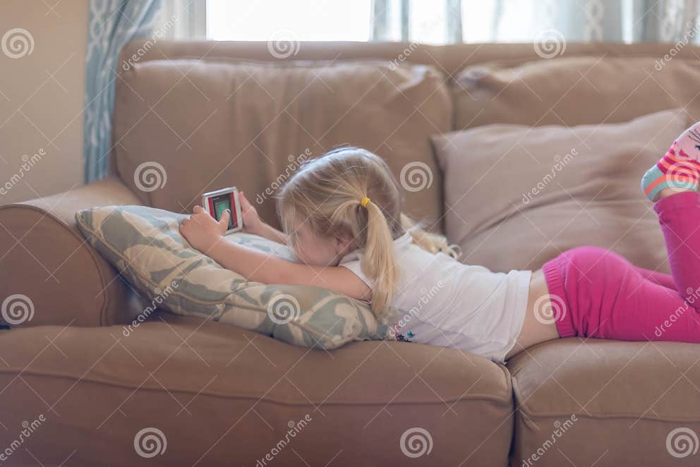 Little Girl Laying on Her Stomach on the Living Room Couch Stock Image