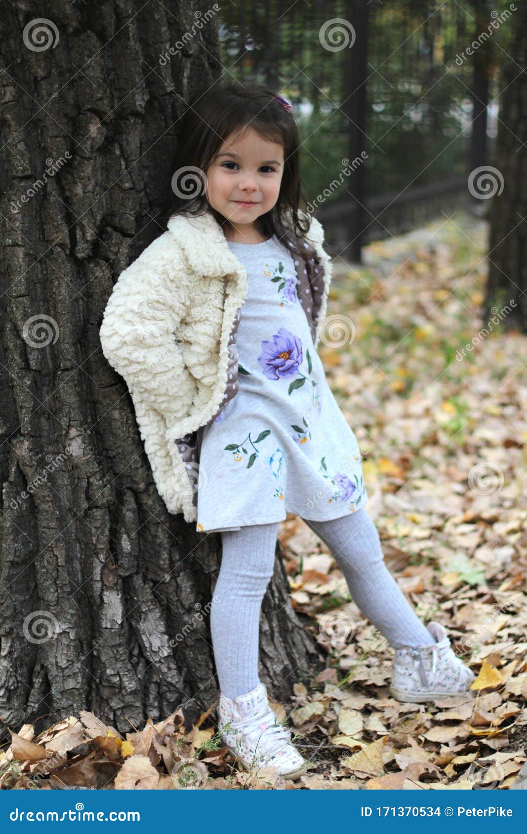 A Little Girl with Long Dark Hair in a Fluffy White Coat and Colorful ...