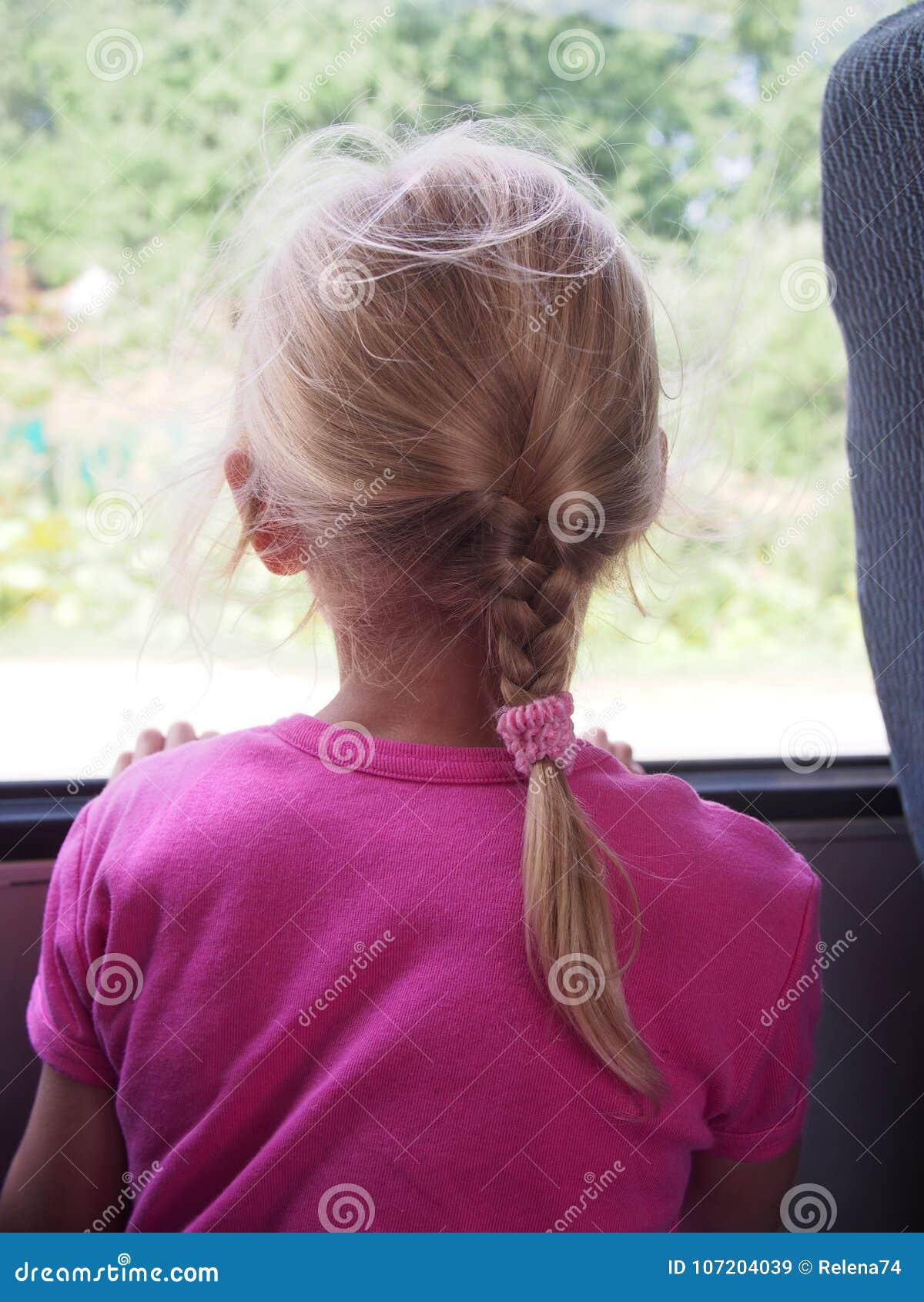 Little girl looking out the window of a bus in summer day