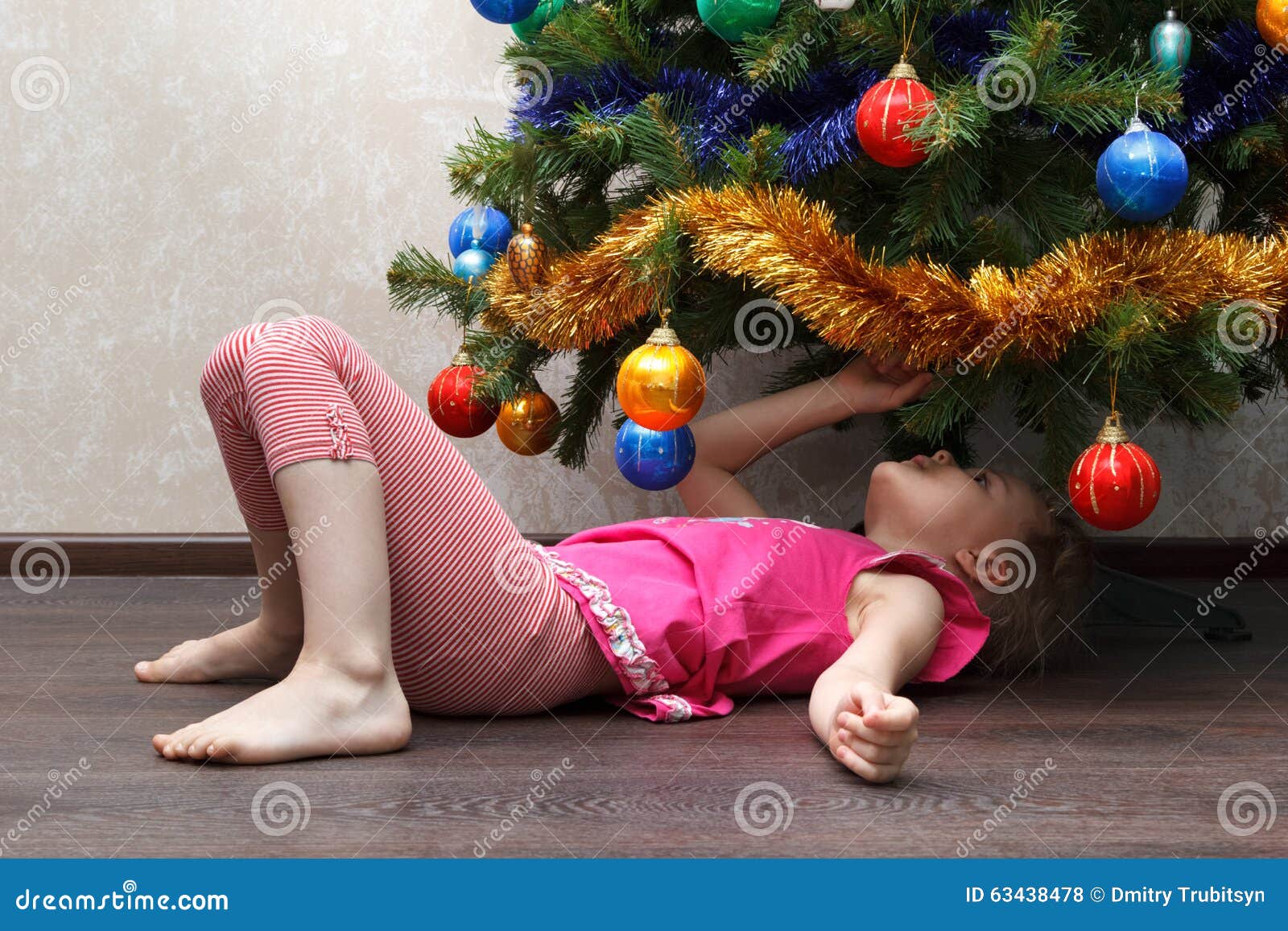Little Girl Lying on Her Back Under Christmas Tree Stock Photo Image