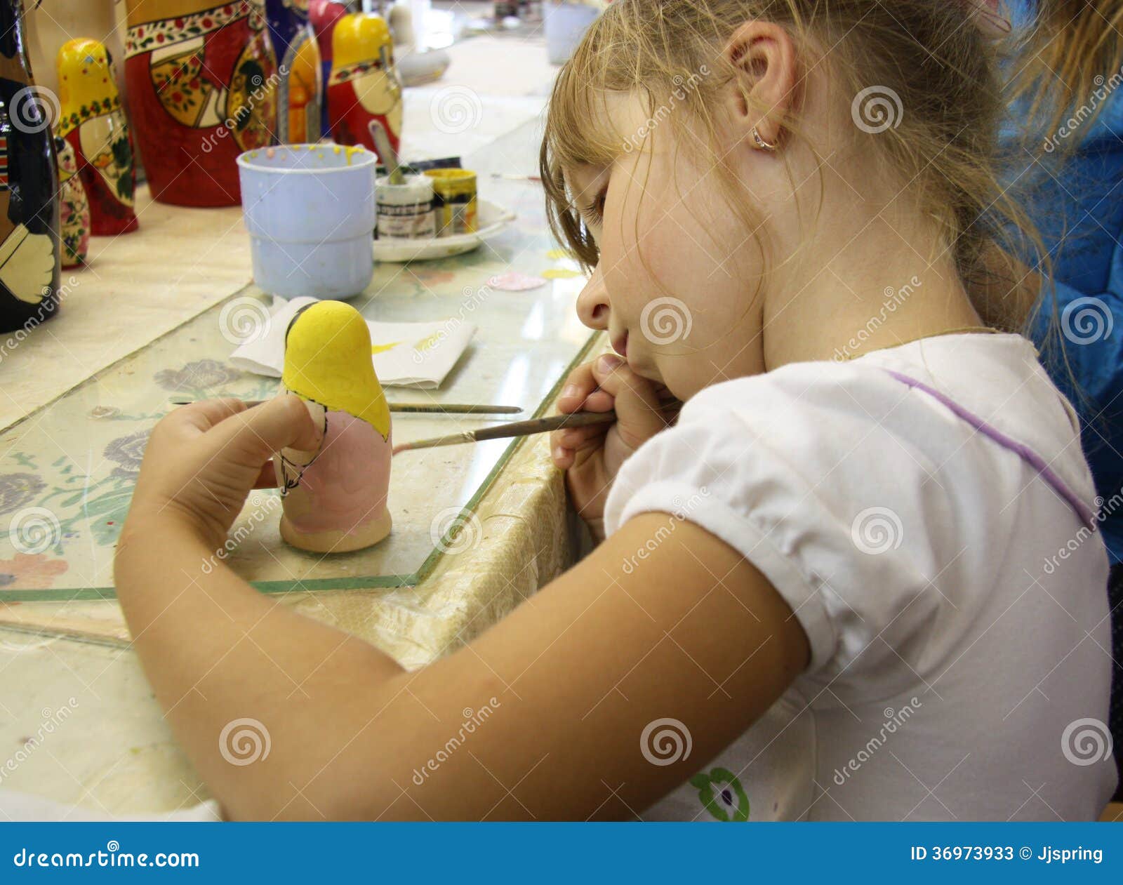 little girl painting a matrioshka russian doll