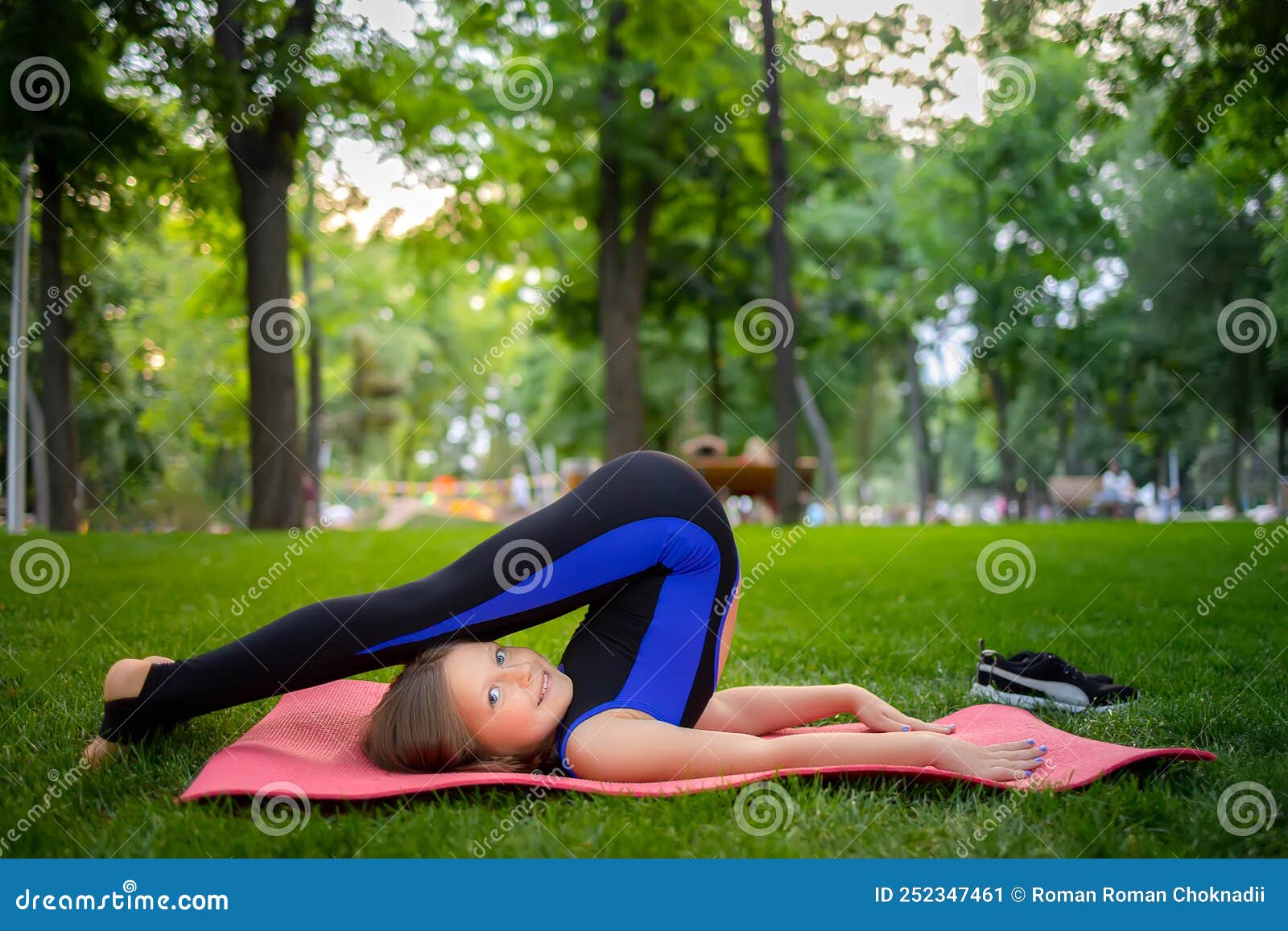 A Little Girl Performs Yoga Elements by Raising Her Legs and Bending ...