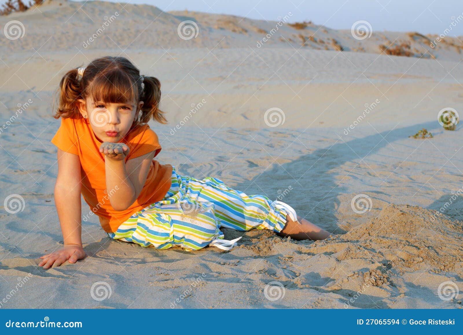 Beautiful little girl playing in sand