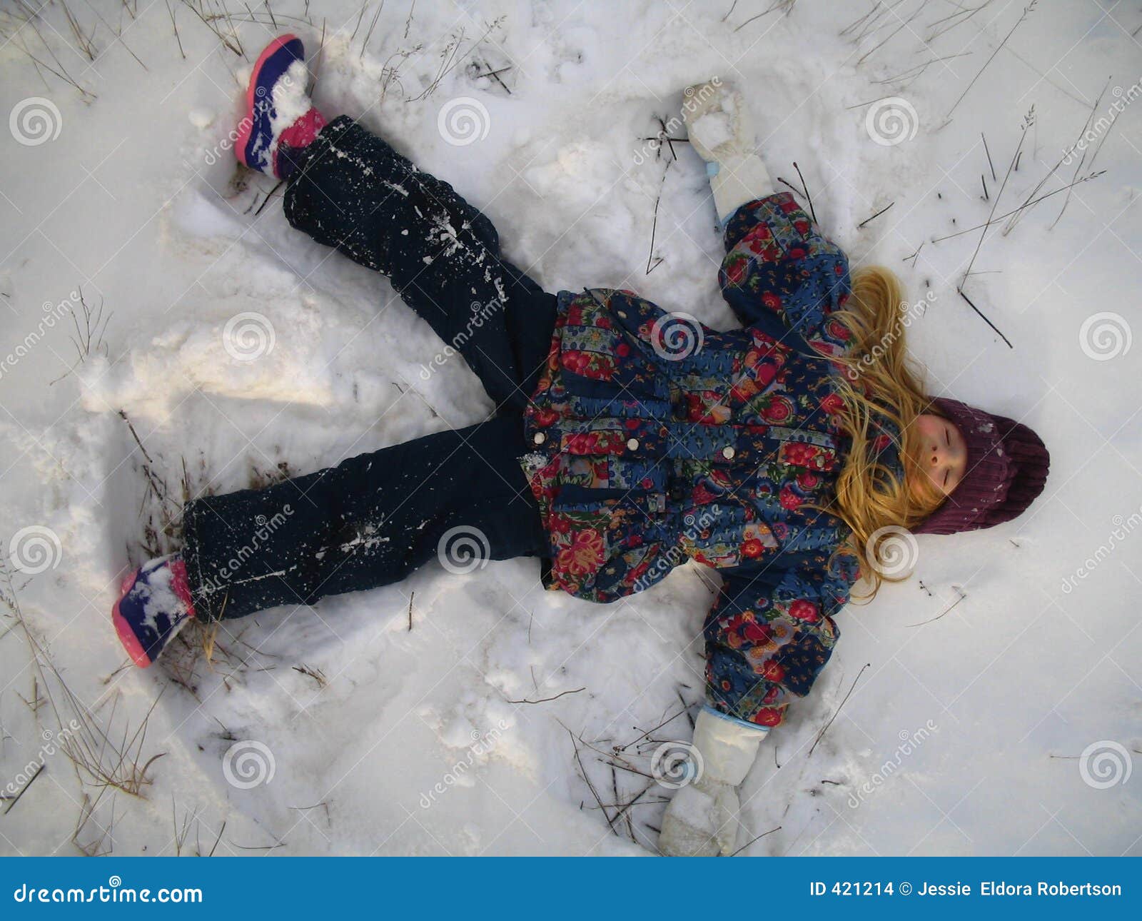 little girl playing snow angel