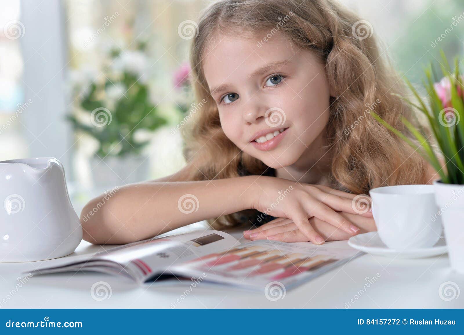Portrait of a little girl reading and drinking tea