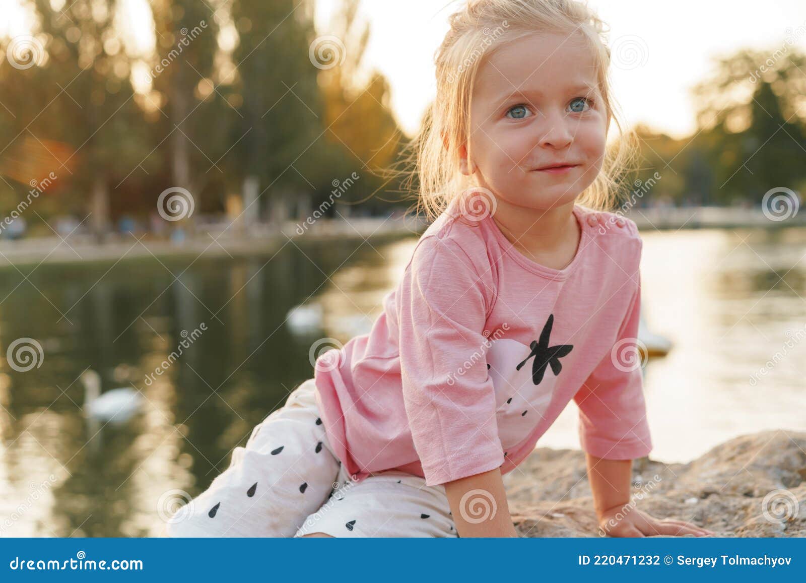 Little Girl Sitting on a Huge Stone in Park Near the Lake Stock Photo ...