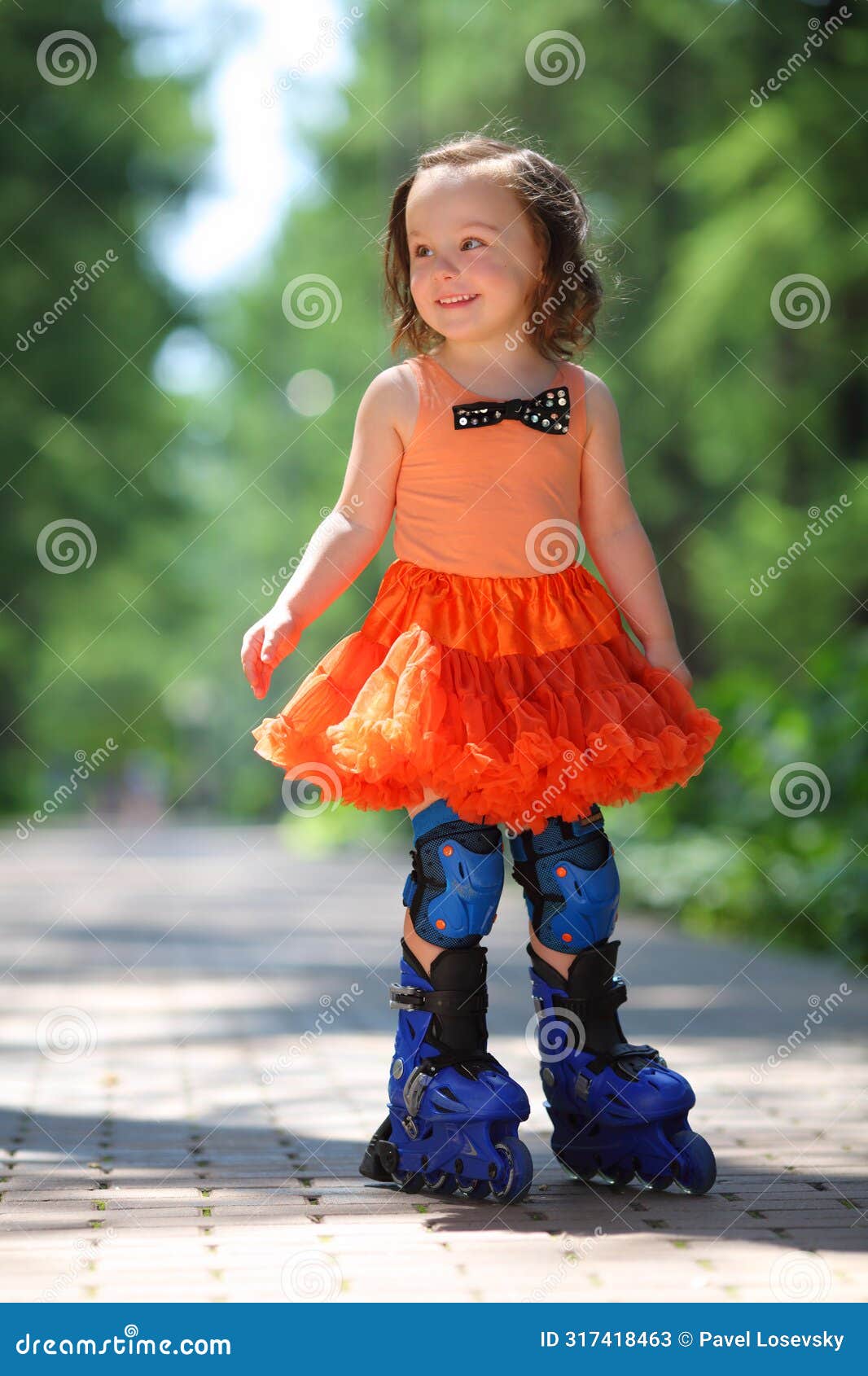 little girl in skirt roller-blades and smiles in