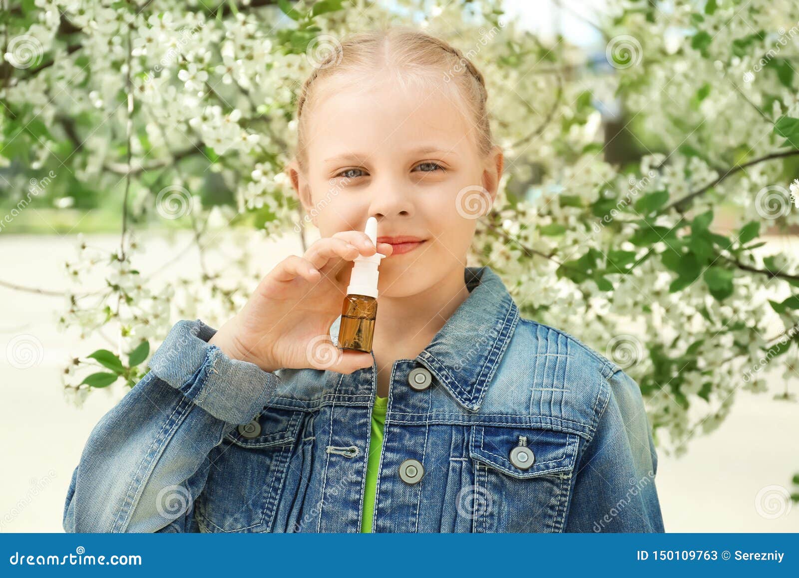 little girl using nasal drops near blooming tree. allergy concept