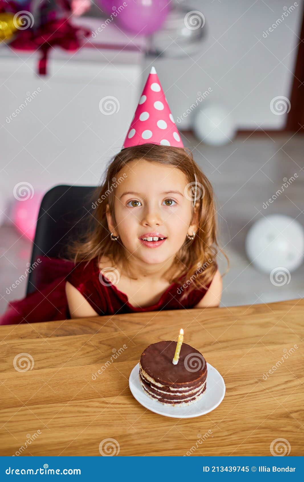 A Little Girl is Wearing a Birthday Hat Makes a Wish , Looking at a ...