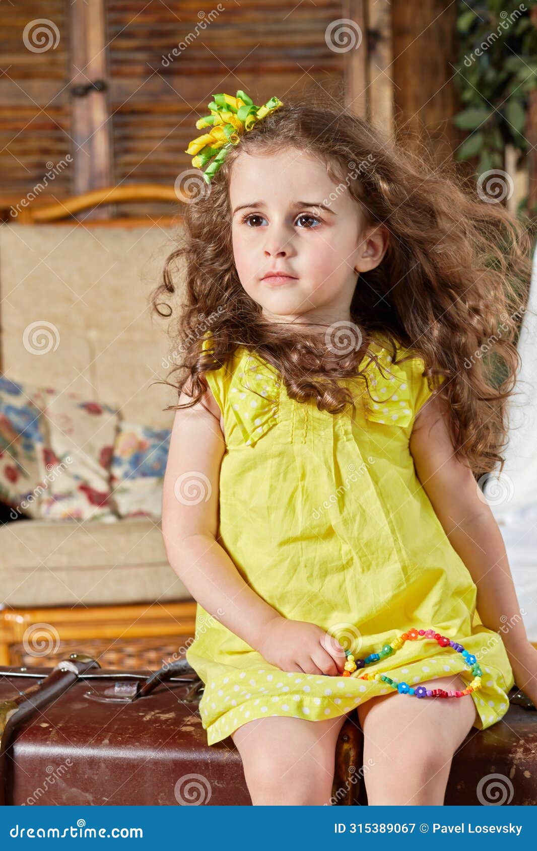 little girl in yellow dress sits on old big ragged