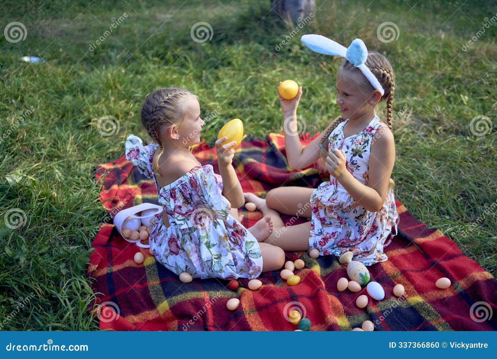 little girls, sisters, playing on a picnic blanket with eggs after an easter egg hunt