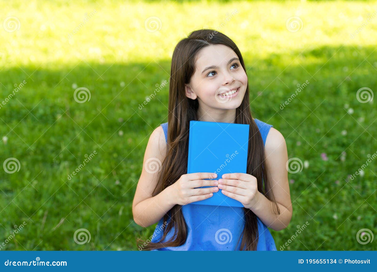 little happy girl reading book outdoors sunny day, daydreamer concept